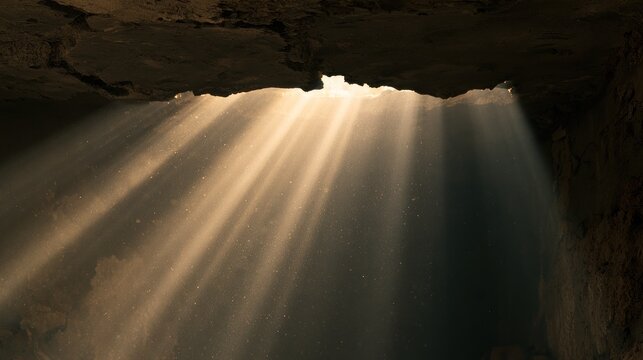 Sunbeams streaming through cave opening illuminating dust particles dark natural setting