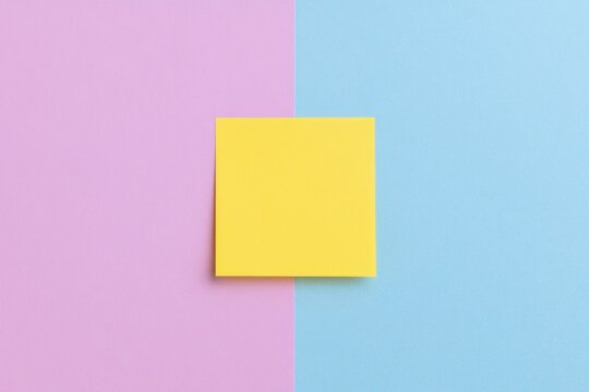 Minimalist flat lay of a yellow sticky note on a split pink and blue background