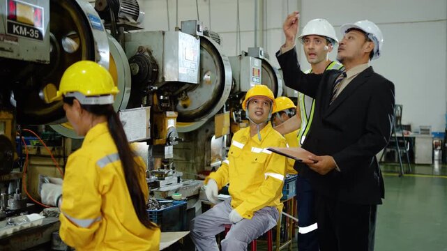 Manager and engineer inspecting industrial manufacturing process with factory workers on production line. Professional team teamwork in metal stamping factory. Modern industrial production concept.