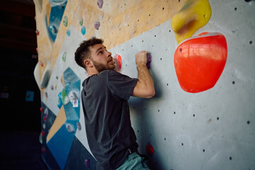 Male climber exercising bouldering on wall in health club. © Drazen
