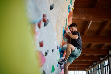 Male boulderer during sports training in climbing gym. © Drazen
