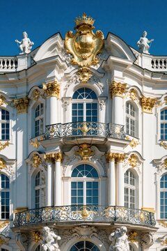 Ornate baroque palace facade with white walls, gold decorations. Historic building features elegant balconies, marble columns, classic sculptures under blue sky. Luxury architecture shows detailed