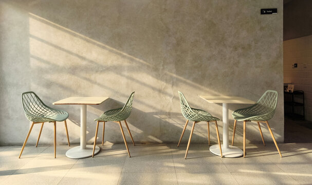 Modern cafe interior with mesh chairs and minimalist tables cast in soft sunlight, architectural photography, urban
