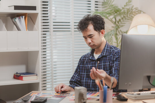 Designer working with color palettes, layout templates, and creative design tools on a desk while planning branding and graphic design projects in a modern office.