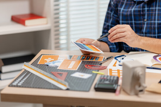 Designer working with color palettes, layout templates, and creative design tools on a desk while planning branding and graphic design projects in a modern office.