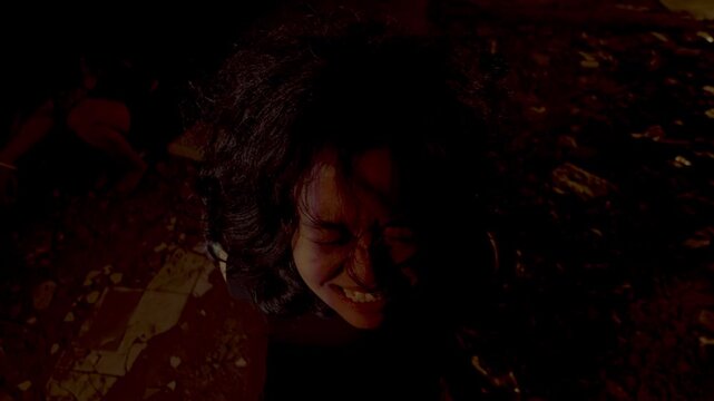 Top-down perspective of a female hostage having an intense emotional breakdown, screaming and crying while looking up at her ruthless kidnapper in a dark, empty space.