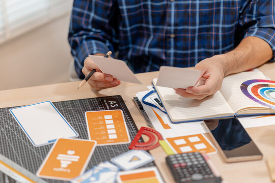 Designer arranging color swatches, layout samples, and branding materials on a creative workspace while planning a visual identity project with notebooks and design tools.