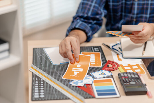 Designer arranging color swatches, layout samples, and branding materials on a creative workspace while planning a visual identity project with notebooks and design tools.