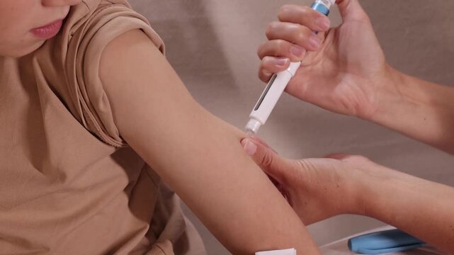 Child receives an somatropin injection in the upper arm