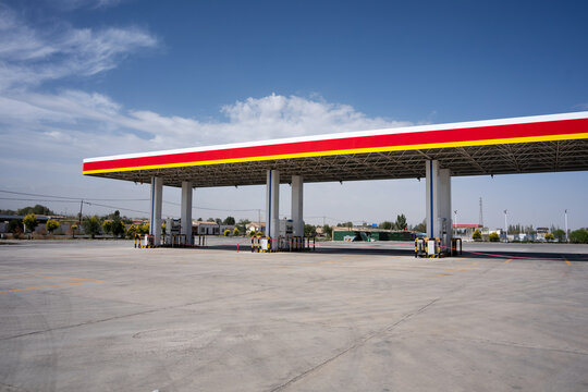 empty shell gas station with red and yellow canopy under blue sky