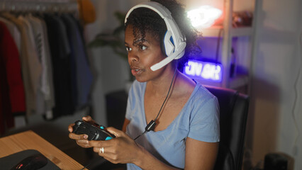 Young woman playing gamepad with headset, mouth open and focused at computer desk in studio  competitive excitement. © Krakenimages.com