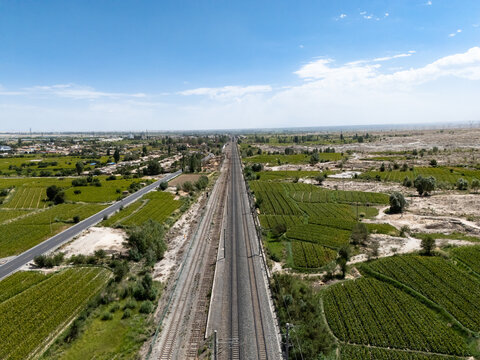 railway and highway passing through green farmland fields