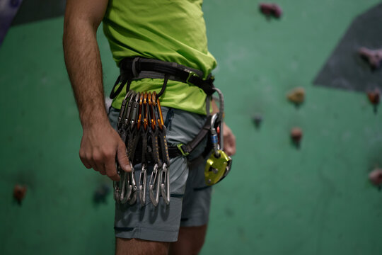 Unrecognizable rock climber wearing harness with carabiners at bouldering club.