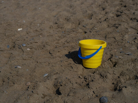 Yellow toy bucket on a sandy beach in summer