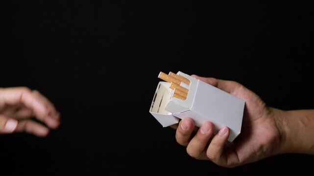 Hand rejecting a cigarette offer on a black background