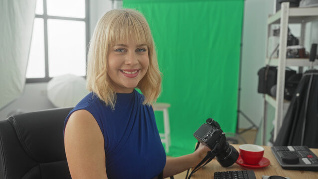 Woman holds dslr camera and types with hands at computer keyboard in studio green screen setup; concentration creativity.