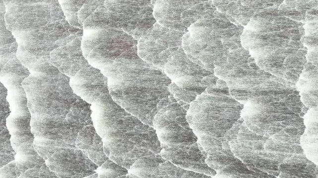 Drone view captures multiple streams of water descending across a dam spillway, symbolizing controlled water release, reservoir safety, flood mitigation and environmental management. 4k.
