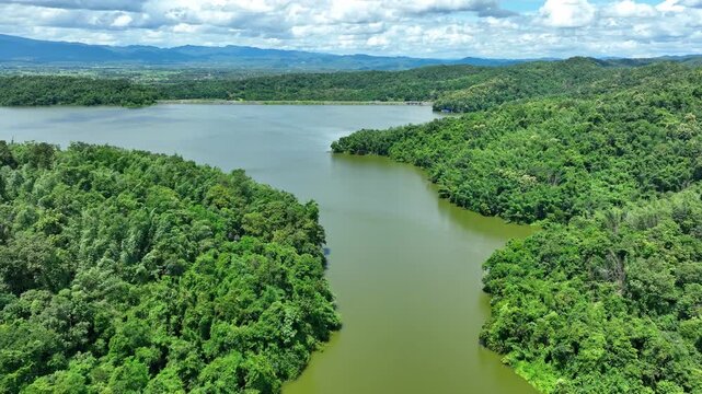 Aerial view shows a freshwater reservoir between densely forested hills, emphasizing watershed ecosystems, water storage, biodiversity and long term environmental protection. Phrae, Thailand. 4k.
