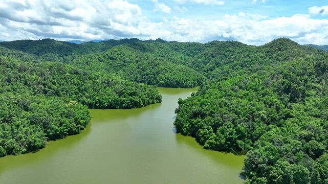 Drone view showcases calm reservoir water surrounded by dense green hills, highlighting watershed protection, biodiversity, water supply and sustainable resource management. Phrae Province, Thailand.
