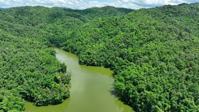 Aerial view captures a vast reservoir surrounded by lush forested mountains, highlighting freshwater resources, watershed conservation and sustainable water management. Phrae Province, Thailand. 4k.

