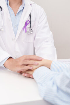 doctor holding patient hand to comfort and support with empathy. purple ribbon for concept of Violence, Pancreatic, Esophageal, Testicular cancer, Alzheimer, Epilepsy, Lupus and Fibromyalgia