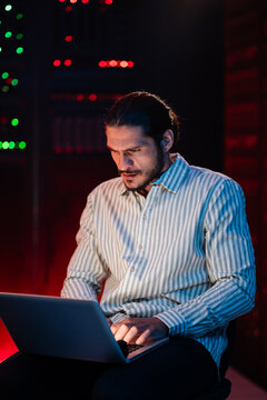 Man working on laptop in server room, cyber security concept