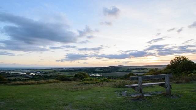 Sunset time lapse at golden hour with fast moving clouds over a coastal town and countryside with a river running through it x2 speed