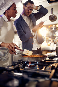 woman chef prepering food and looking at orders. Cook in Professional Modern  kitchen, restaurant concept