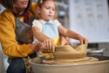 Hands of student and teacher making a pot from clay at pottery workshop.  Creative, hobby ,workshop  concept © luckybusiness