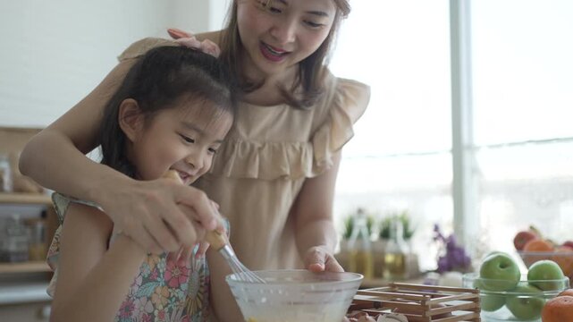 Mother and daughter smiling while whisking egg mixture together