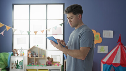 Man tapping tablet screen with finger while holding device in a toy filled room in building  quiet concentration. © Krakenimages.com