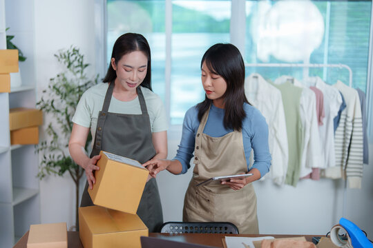 Asian business partners checking parcel box and tablet for online shop delivery