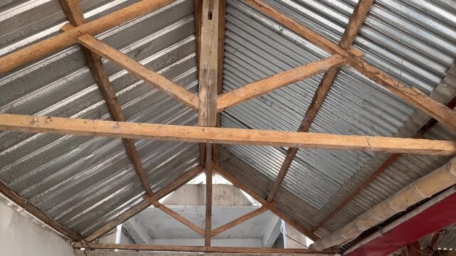 Symmetrical view of wooden roof structure with corrugated zinc sheets