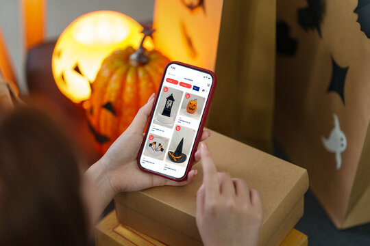 Entrepreneur using smartphone app for Halloween online shopping at home