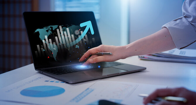 Businessperson analyzing global market growth chart overlay on laptop at office desk