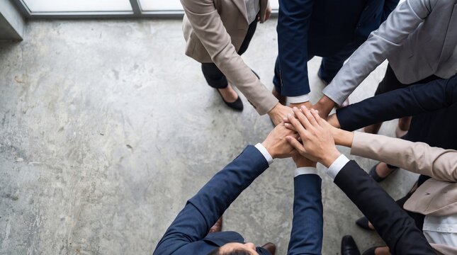 Business team hands stacked together symbolizing unity indoors