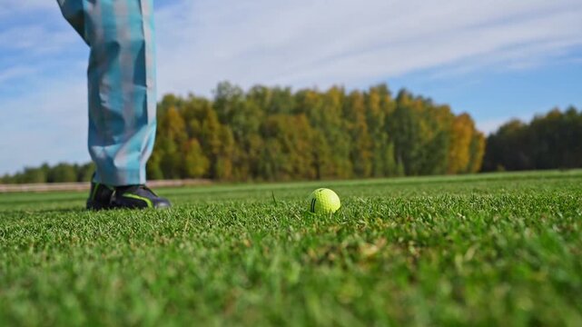 Focused man practicing golf swing on driving range with greenery in background. Outdoor recreational activities and sports training.
