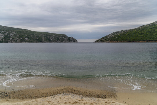 Enclosed natural harbour of Porto Koufo with its narrow rocky entrance between two headlands under a grey sky, Sithonia, Chalkidiki, Greece