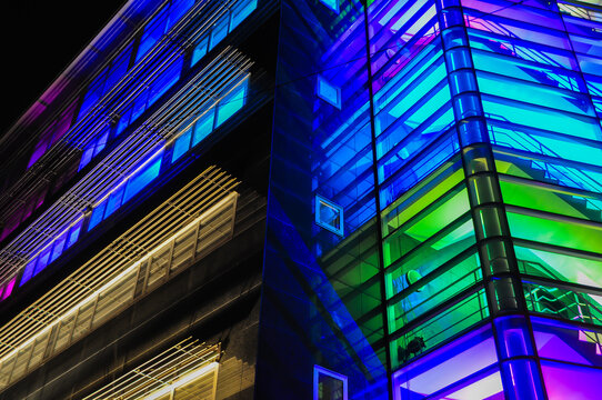 modern office building with glass, stairs and neon bright lights in blue, green and purple colors