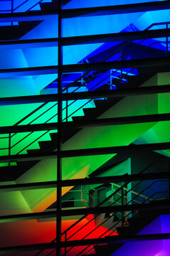 abstract background of building with glass, metal and staircase in colored neon night lights