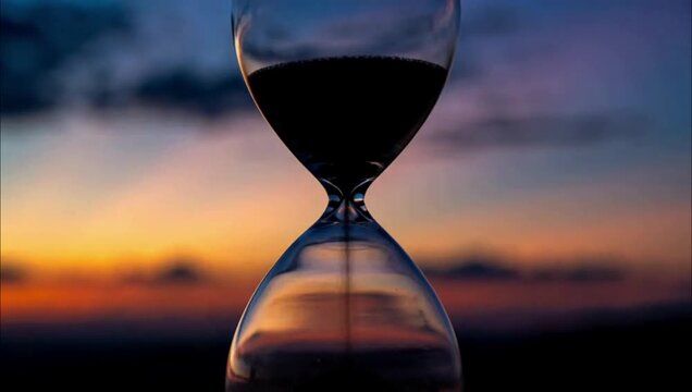 An hourglass silhouette against a beautiful sunset sky representing the passage of time.