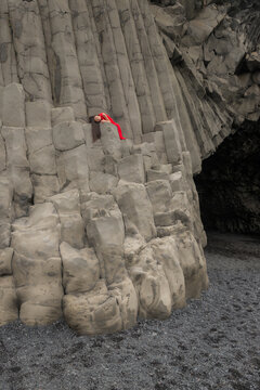 art portrait of girl in red dress on basalt columns of Reynisfjara beach, Vik, iceland