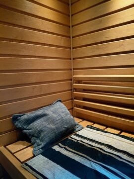 Cozy wooden sauna interior with blue cushion and striped bench towel