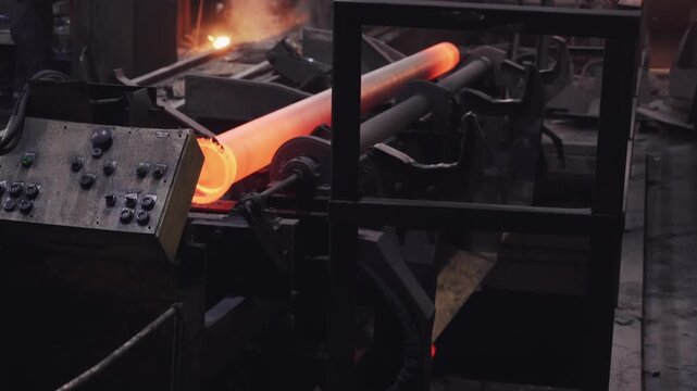 Ductile iron pipe on hot transfer line after casting, moving on roller conveyor in foundry toward annealing for water infrastructure production.