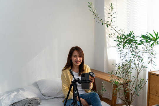 Woman showing a paper coffee cup to a smartphone set on a tripod