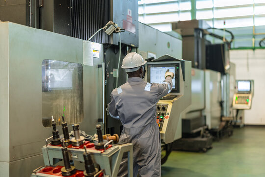 Black Engineer Operating CNC Machine in Factory Checking Industrial Manufacturing Process Control