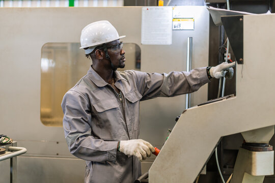 Black Engineer Operating CNC Machine in Factory Checking Industrial Manufacturing Process Control