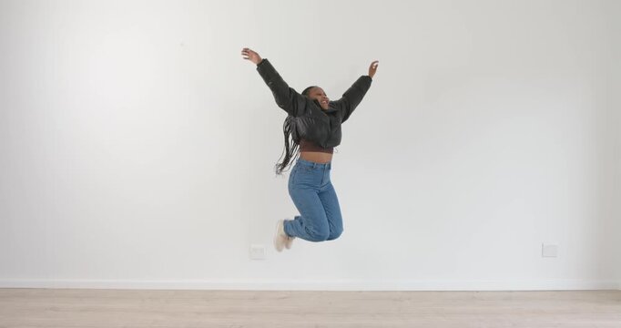 High-speed photography for dynamic scenes, jumping joyfully, woman in casual outfit posing against w