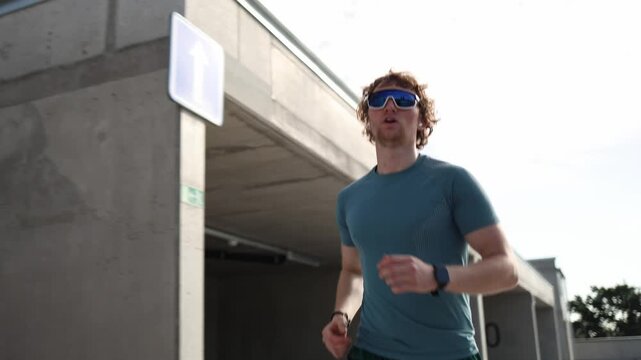 Young athlete keeps running despite growing fatigue pushing himself through a demanding outdoor cardio workout and building endurance with every step during hard training