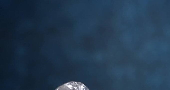 Ice cube falling in slow motion on blue background